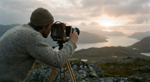 Fotograf justerar kamerans objektiv på stativ i gyllene solnedgång, med syfte att förmedla ett budskap.